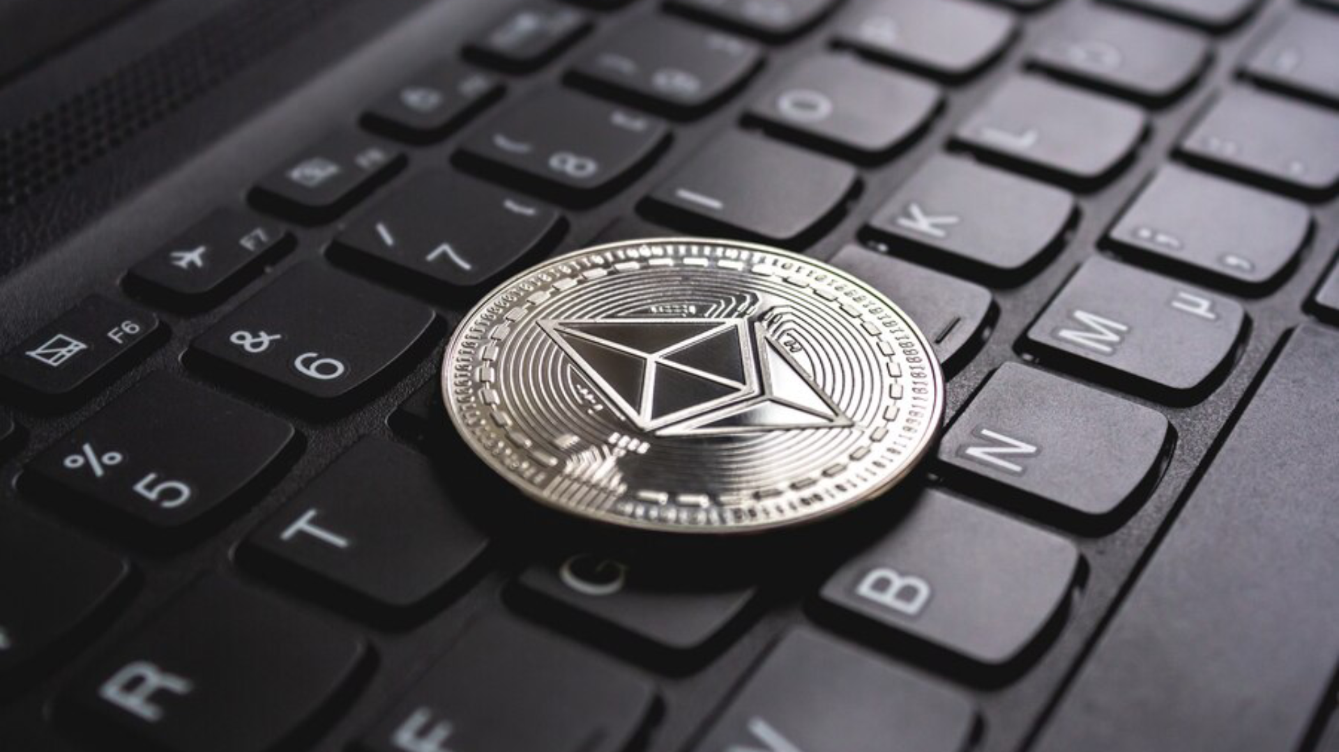 Ethereum coin at the top of laptop.